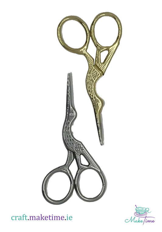 Pair of stork scissors with one gold and one silver design on a white background.