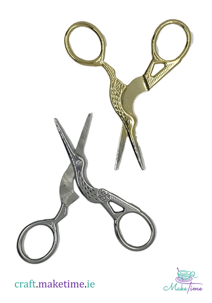 Two Pairs scissors, one gold and one silver, on a white background.